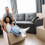 girl sitting in box happy with her hands up while guy pushes box 