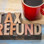 tax refund in wood letters on table with red coffee mug