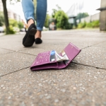 woman walking away from dropped wallet on ground 